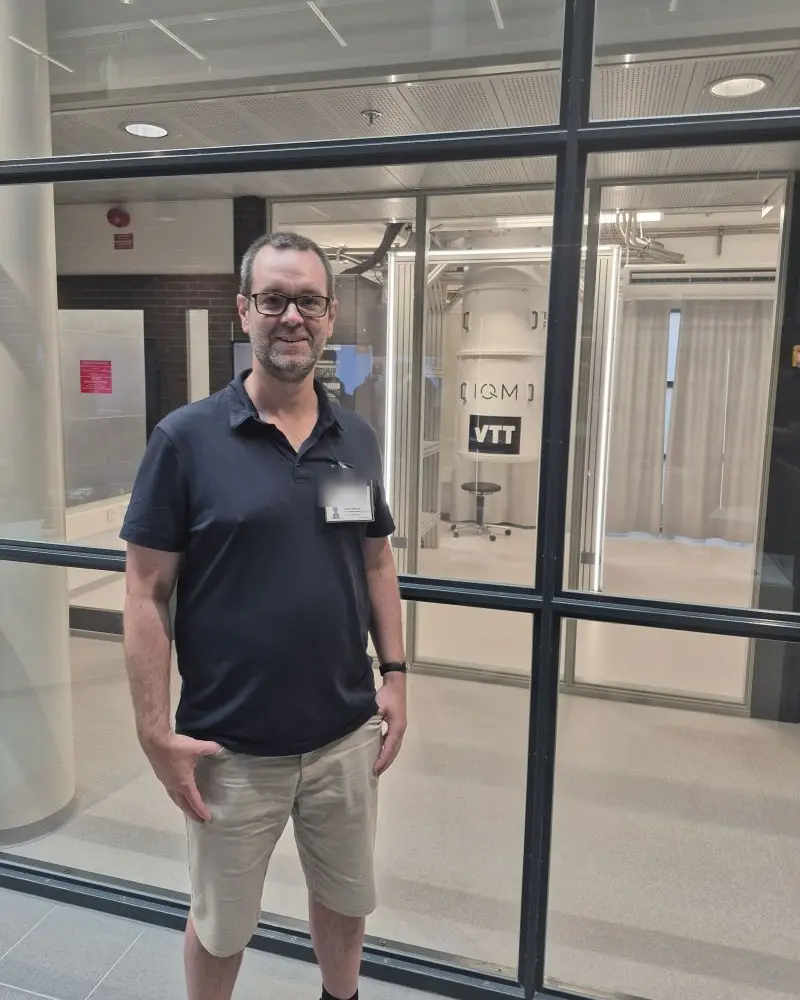 Julen Larrucea standing in front of an IQM quantum computer at VTT in Espoo, Finland.